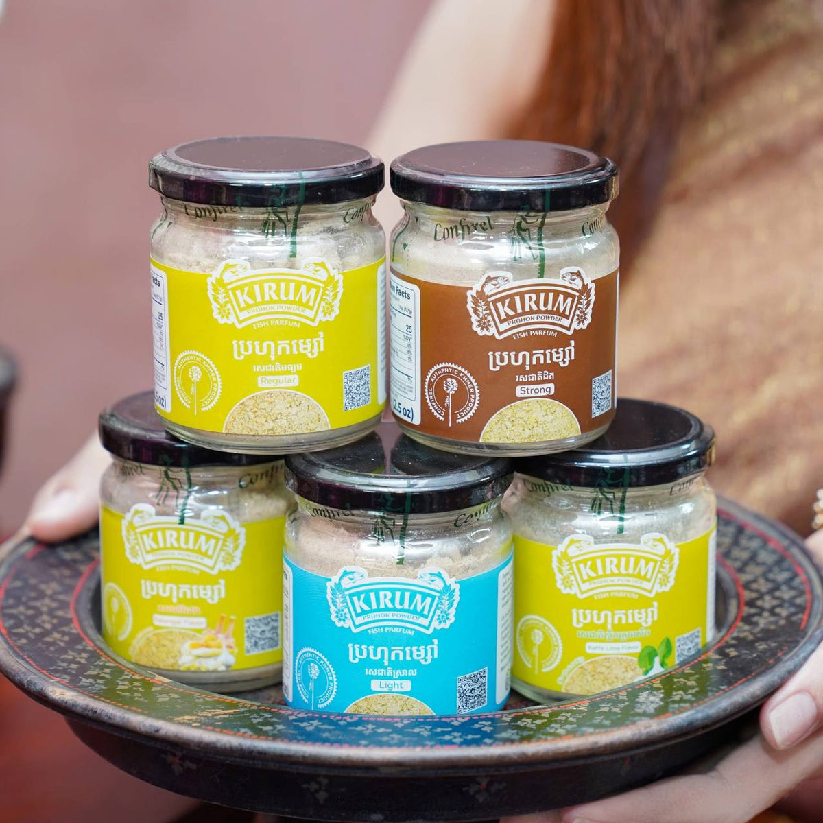 Five jars of Kirum prahok powder in assorted flavours displayed on a tray