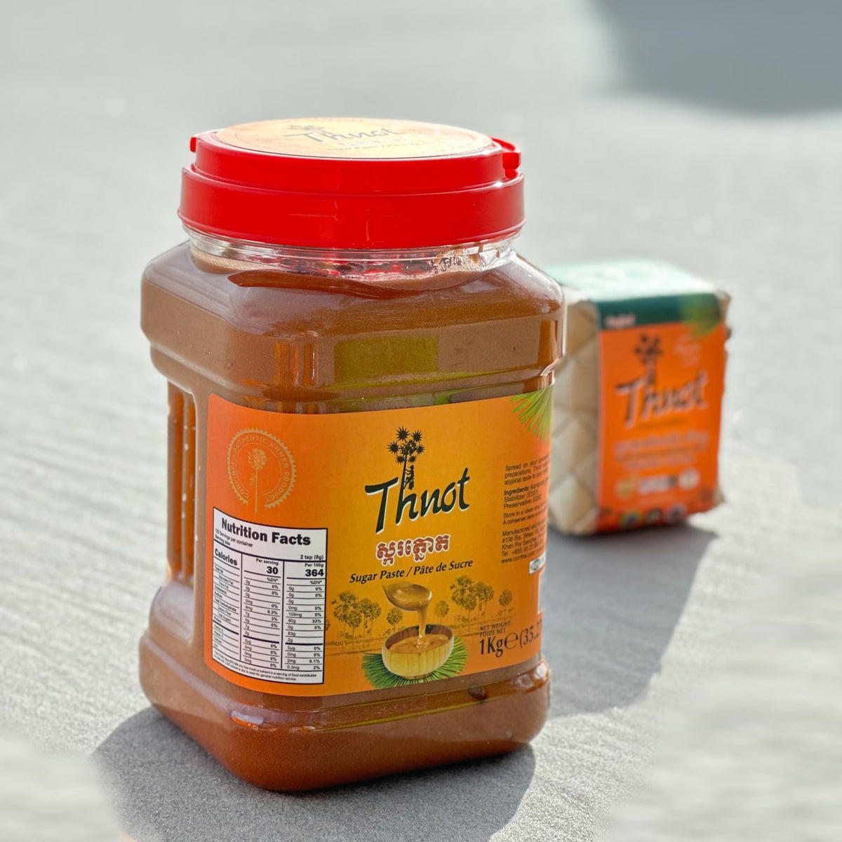 Jar of Thnot palm sugar paste, 1kg, with a woven sugar block in the background